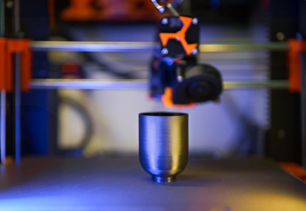Innovative close-up of 3D printer crafting a metallic object, showcasing modern technology.